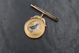 An early 20th century 9ct gold racing pigeon medal having a central painted ceramic panel and