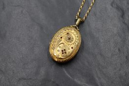 A Victorian large oval yellow metal locket having seed pearl and red paste stone floral decoration