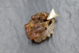 A Chinese carved white and rust jade style pendant depicting two fish and a lily pad with a