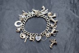 A silver curb link charm bracelet, having eighteen charms including a spider, a double fish,