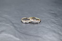 A pair of 9ct gold loop earrings, each having a trio of claw set white paste stones, approx 2g