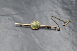 An 18ct gold Chinese jade set bar brooch, the central jade disk in a gold bezel setting with the