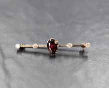 A white metal garnet and diamond set bar brooch, the central pear cut garnet flanked by two bezel