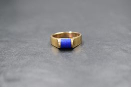 A 9ct gold lapis lazuli set ring, the central domed rectangular lapis lazuli panel in a raised