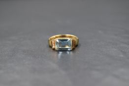 A yellow metal aqua marine and diamond ring having a central emerald cut aqua marine of approx 2ct