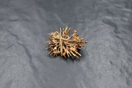 A 9ct gold brooch of stylised starburst form having diamond and ruby chip decoration, approx 9.6g