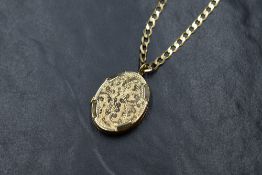 A 9ct gold oval locket having scroll and moulded decoration, on a 9ct gold 18' flat curb link chain,