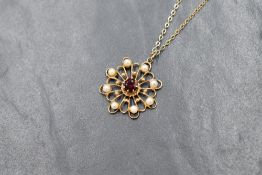 A 9ct gold red paste and pearl set pendant, the central round cut paste in a openwork floral motif