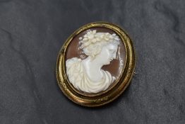 A conch shell cameo brooch depicting a Grecian maiden in profile, in a decorative pinchbeck mount,