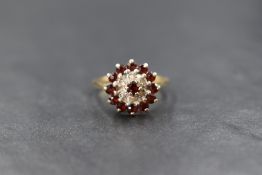 A 9ct gold garnet and diamond set cluster ring, the central round cut garnet with a diamond chip