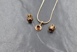 A 9ct gold garnet set necklace and stud earrings suite, the round cut garnet in a bezel setting