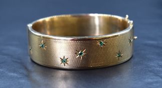 A mid 20th century 9ct gold hinged bangle having engine turned decoration and seven small inset