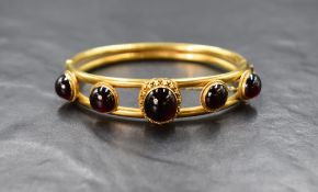 A high carat gold garnet set hinge bracelet, the five graduated garnet cabochons in bezel settings