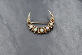 A 9ct gold opal set crescent brooch, the five opal cabochons in a decorative pierced crescent,
