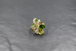 A 9ct gold multi stone green open cluster ring having diamond chip set ribbon decoration on a 9ct