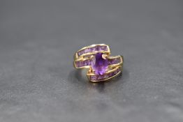 A 9ct gold amethyst ring by QVC having a central oval amethyst on a princess cut amethyst set band