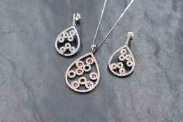 A silver cubic zirconia and ruby necklace and drop earring set, the modern cubic zirconia set pear