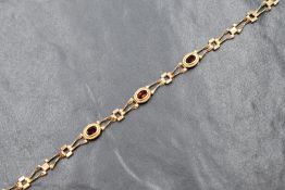 A 9ct gold garnet set bracelet, the three oval cut garnets in bezel settings with rope decoration,
