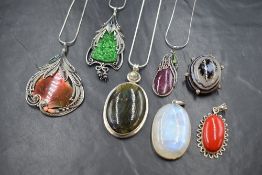 Seven mixed polished mineral pendants of various styles, all in white metal mounts, four having