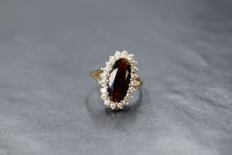 A 9ct gold oval garnet and cubic zirconia cluster ring in a stepped claw set mount to split