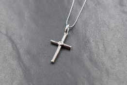 A 9ct white gold cross pendant of tubular form with a central inset diamond, approx 0.05ct on a