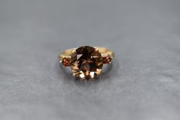 A 9ct gold smoky quartz and garnet set ring, the central round cut smoky quartz measuring