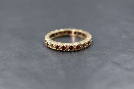 A 9ct gold garnet set full eternity band, the round cut garnets in claw settings, marked 9ct, ring