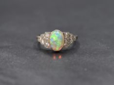 An Edwardian 18ct white gold opal & diamond ring having a central opal cabochon in a collared