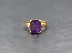 An 18ct gold amethyst ring having an emerald cut heat treated amethyst in a four claw set basket