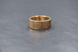 A 9ct gold band, of wide form with textured decoration, marked 375, ring size Q, 7g