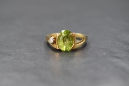 An 18ct gold peridot and diamond artisan style ring, the central oval peridot being set in a tension