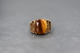 A 9ct gold tiger's-eye and smoky quartz set ring, the central tiger's-eye cabochon flanked by two