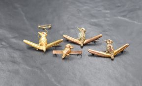 A group of four 9ct gold kookaburra motif brooches, three perched on boomerangs having gem set