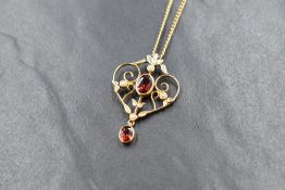 A 9ct gold modern Edwardian style garnet and seed pearl set pendant, the openwork pendant having a