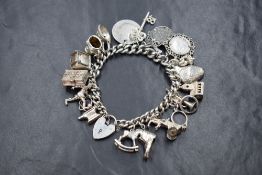 A silver curb link charm bracelet, having twenty-one charms including a rocking horse, a trumpet,