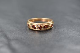A 9ct gold garnet set ring, the central round cut garnet flanked by two pear cut garnets and a
