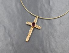 A yellow metal presumed gold garnet set cross pendant, the central oval cut garnet in a bezel