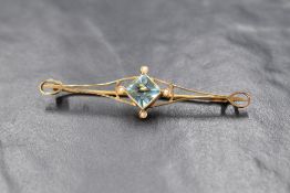 A yellow metal open bar brooch stamped 9ct having a central pale blue paste stone with seed pearls