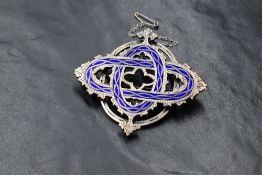 A white metal and enamel oversized brooch of 3D form having blue enamel and shaped decoration, no