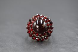 A yellow metal presumed gold Bohemian garnet set cluster ring, the central cabochon in a two tier