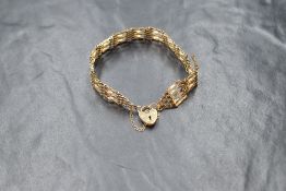 A 9ct gold five bar gate bracelet with padlock clasp and safety chain, approx 5.4g (damage to one