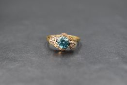 An 18ct gold blue zircon and diamond set three stone ring, the central round cut zircon measuring