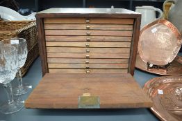 A 20th century stained wood coin/token collectors chest, having a fall-front enclosing ten drawers