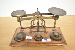 A 20th-century brass and wood post office scale, accompanied by 6 brass weights. 22.5cm