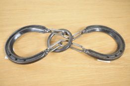 A forged iron horse shoe puzzle, having two horse shoes and connecting links with a rounded hoop,