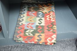 An Afghan flatweave kilim type fringed rug, decorated with repeating designs in polychrome 125cm x