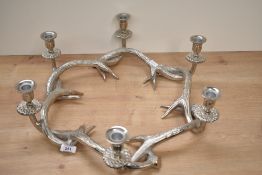 A decorative white metal multi-sconce table top candle holder, formed as a ring of entwined antlers,