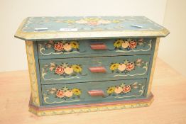 A small decorative painted-pine three drawer chest, of canted oblong form and painted with floral
