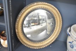 A large late 20th-century wood oval gilt pothole type mirror, having a ebonised inner rim mirror