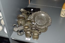 A group of six antique pewter measures, jug, two plates and two swan form pin cushions